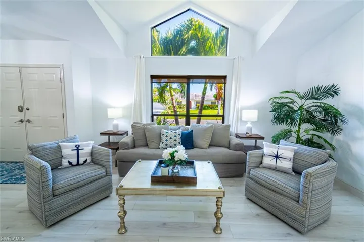 Living room with high vaulted ceiling and light wood-type flooring