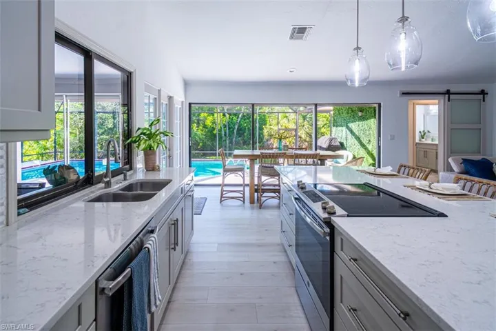 Kitchen with appliances with stainless steel finishes, healthy amount of natural light, light wood-style flooring, and light stone countertops