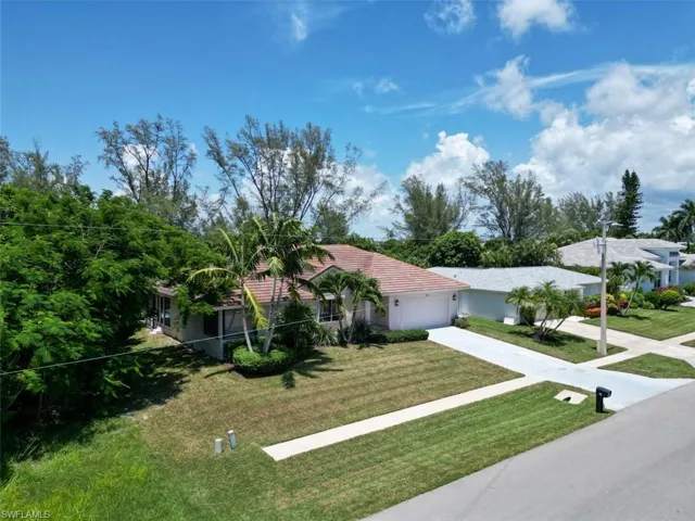 View of front facade featuring a garage, driveway, a front lawn, a tiled roof, and stucco siding