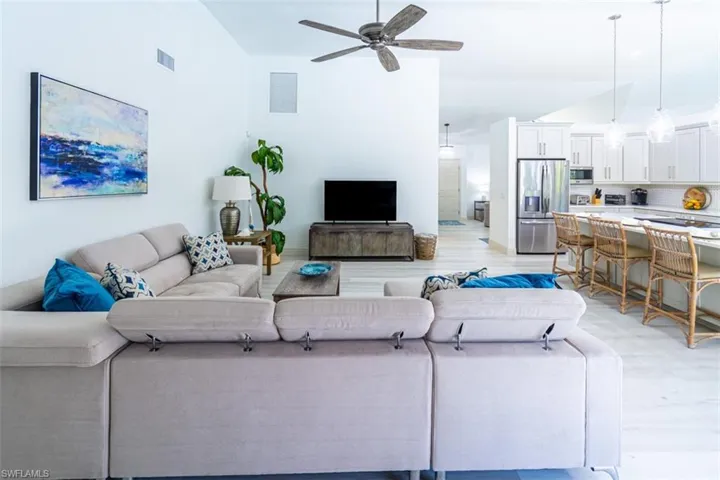 Living area featuring ceiling fan, light wood-style floors, and high vaulted ceiling
