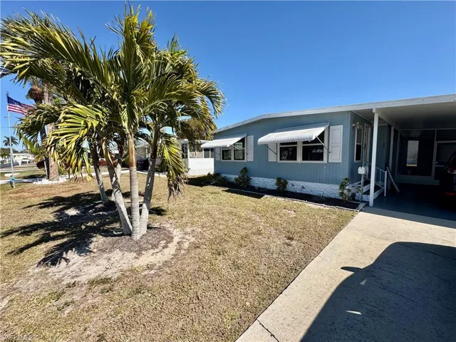 View of side of property featuring driveway, a yard, and an attached carport