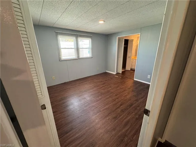 Primary bedroom featuring dark wood-type flooring and baseboards