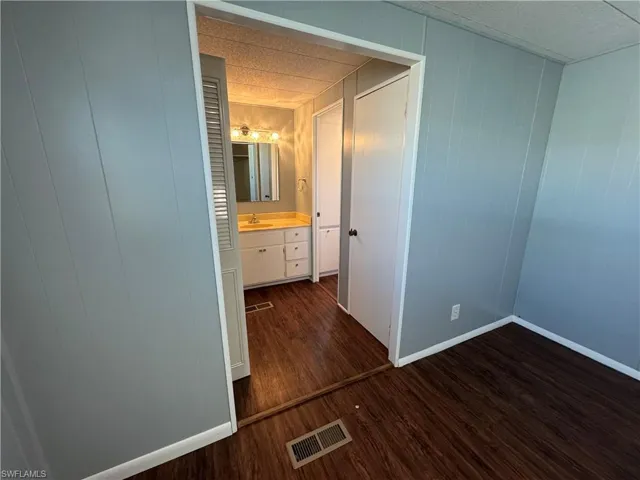 Primary bedroom / bathroom with dark wood-style flooring and ensuite bath