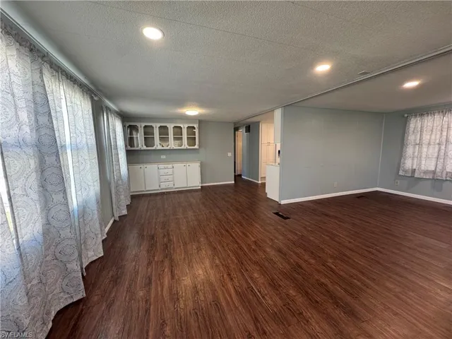 Unfurnished living room / dining room with dark wood finished floors, a textured ceiling, and recessed lighting