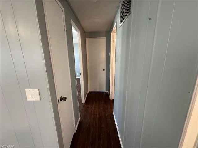 Corridor with dark wood-style flooring and baseboards
