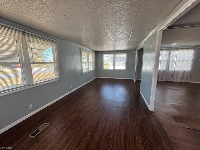 Empty room featuring a drop ceiling and dark wood-style flooring
