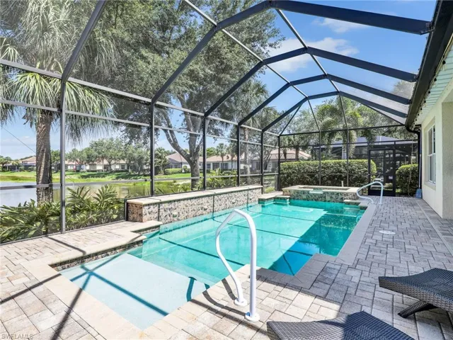 View of swimming pool with a patio, glass enclosure, and a pool with connected hot tub