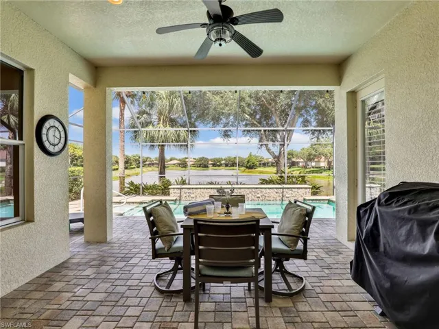 View of patio with an outdoor pool, ceiling fan, a water view, glass enclosure, and outdoor dining area