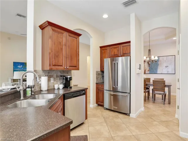 Kitchen featuring stainless steel appliances, a sink, decorative backsplash, a chandelier, and arched walkways