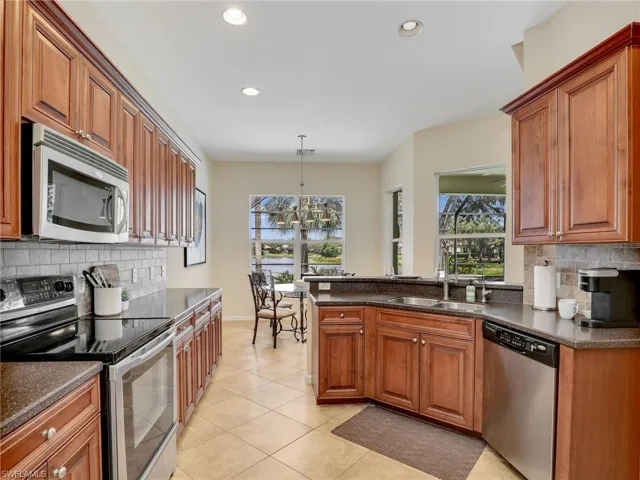 Kitchen featuring appliances with stainless steel finishes, a sink, tasteful backsplash, light tile patterned flooring, and recessed lighting