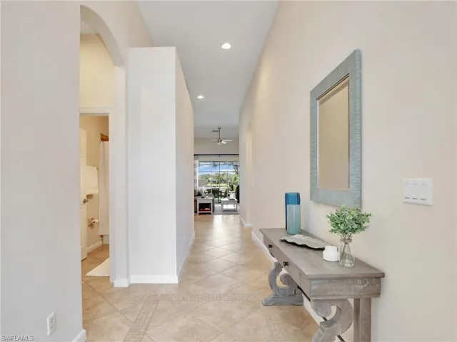 Corridor with recessed lighting, light tile patterned flooring, baseboards, and arched walkways