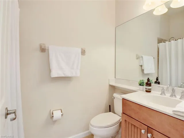 Bathroom featuring toilet, vanity, and a shower with curtain