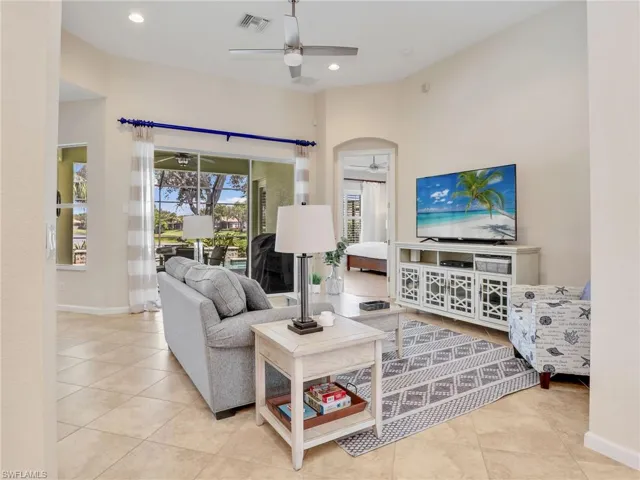 Tiled living room featuring ceiling fan, arched walkways, baseboards, and recessed lighting
