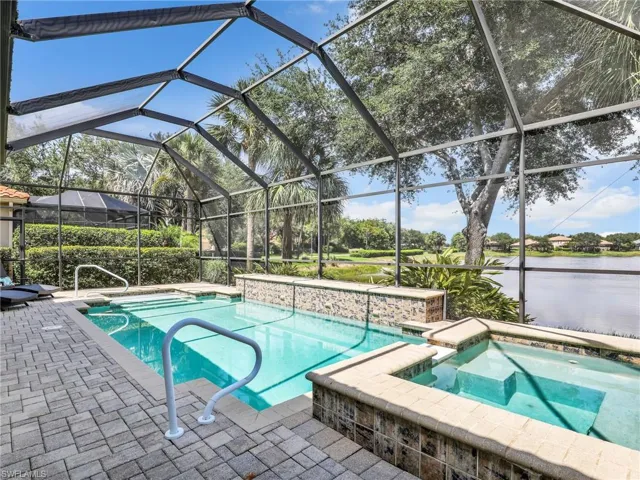 View of swimming pool featuring a patio area, a water view, and glass enclosure