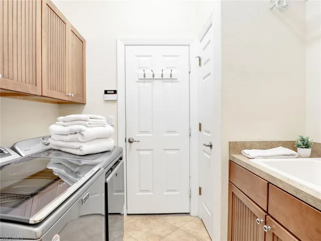 Laundry room with washer and clothes dryer, cabinet space, and light tile patterned flooring