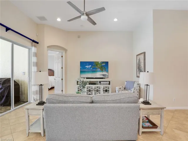 Living room with arched walkways, ceiling fan, light tile patterned floors, and recessed lighting
