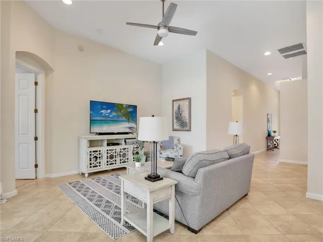 Living area featuring arched walkways, ceiling fan, light tile patterned flooring, recessed lighting, and baseboards