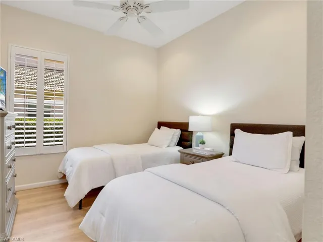 Bedroom featuring light wood finished floors, baseboards, and a ceiling fan