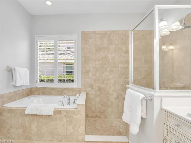 Bathroom with a bath, vanity, and a walk in shower
