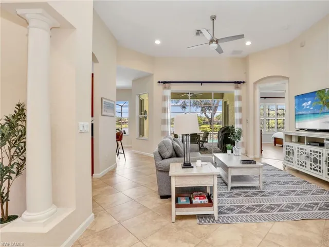 Living area featuring ceiling fan, ornate columns, arched walkways, light tile patterned floors, and recessed lighting