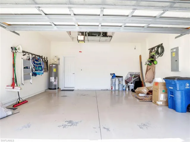 Garage featuring electric water heater, a garage door opener, and electric panel