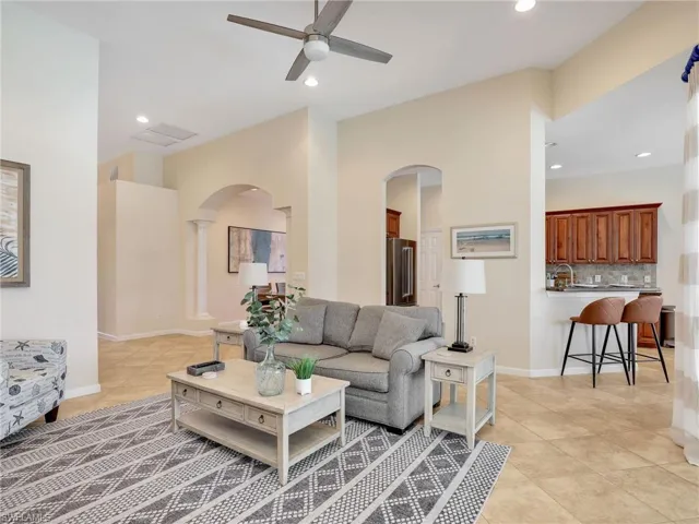Living room with light tile patterned flooring, arched walkways, ceiling fan, recessed lighting, and decorative columns