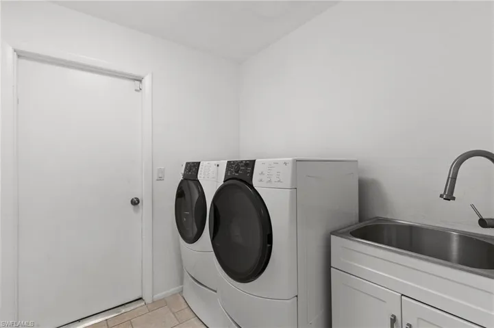 Laundry room with washing machine and dryer and light tile patterned flooring
