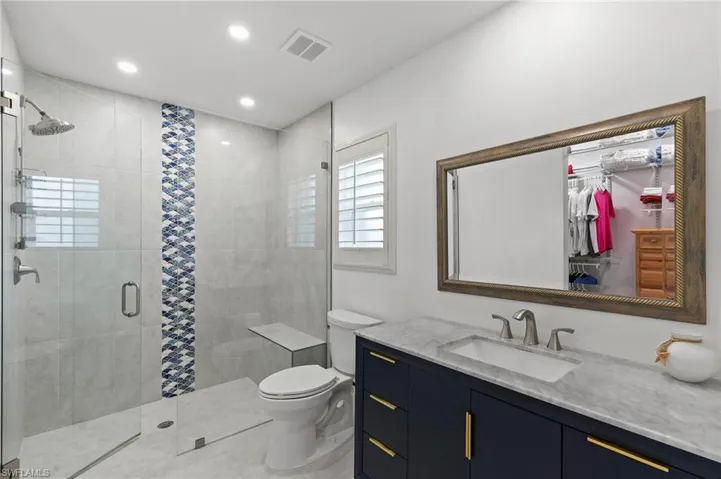 Full bath with a stall shower, vanity, a spacious closet, and recessed lighting