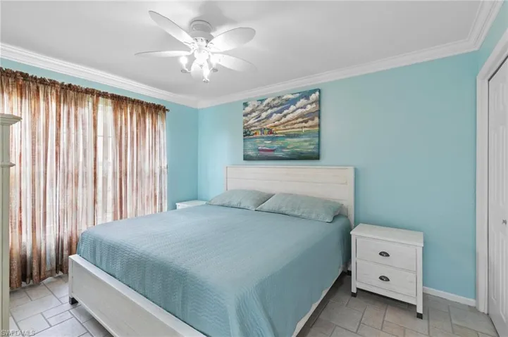 Bedroom featuring crown molding, a ceiling fan, tile floors, and a closet