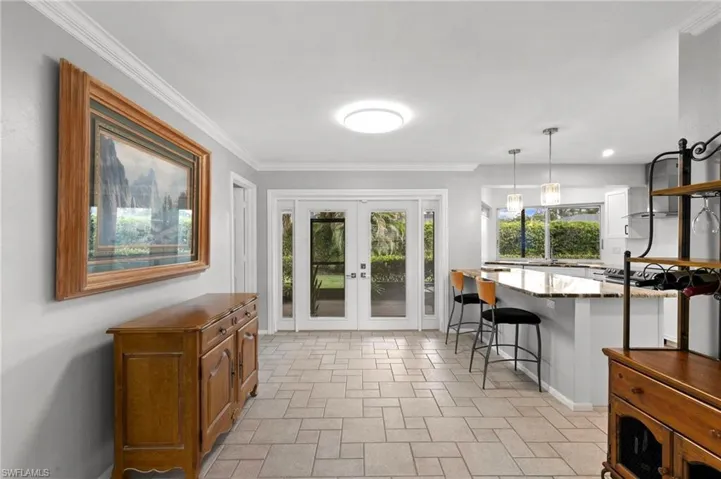 Doorway to outside with ornamental molding, french doors, and stone finish flooring