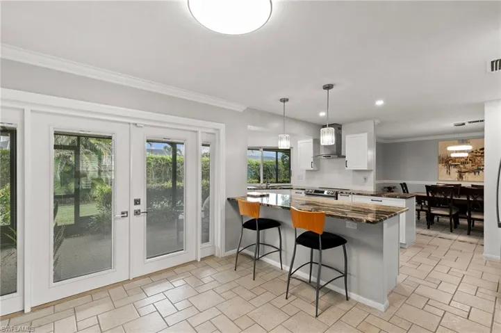 Kitchen with white cabinetry, ornamental molding, a breakfast bar, pendant lighting, and a peninsula