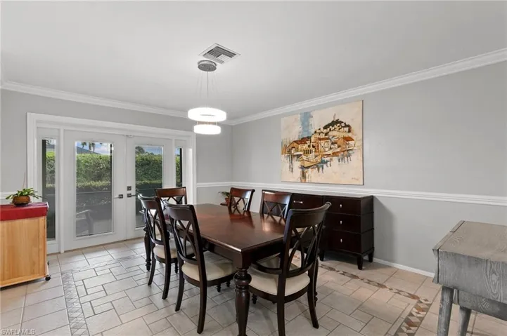 Dining space featuring inlaid floor details, ornamental molding, and french doors