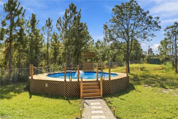 Above-ground circular pool featuring a wood-lattice skirt, wrap-around timber decking, nautical rope railing, and integrated stairs