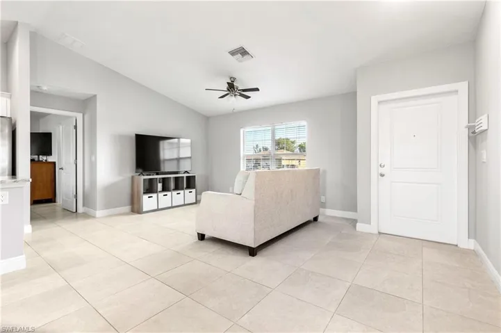 living room with ceiling fan, lofted ceiling, and light tile patterned flooring
