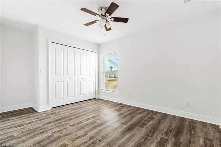Unfurnished bedroom with a closet, ceiling fan, recessed desk area and hardwood / wood-style flooring