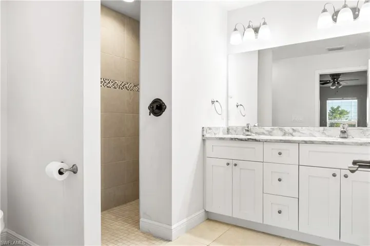 Bathroom with a tile shower,  tile patterned floors, and vanity