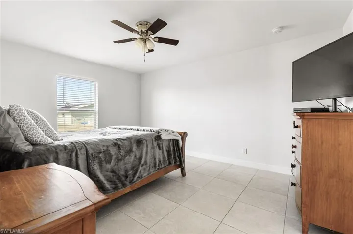 Bedroom with ceiling fan and light tile patterned floors