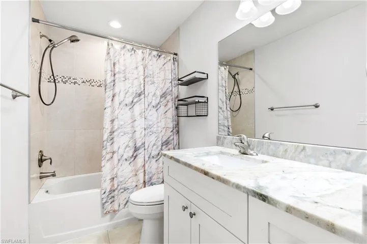Full bathroom featuring tile patterned flooring, shower / tub combo with curtain, vanity, and toilet