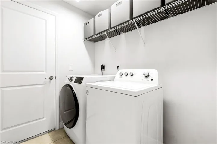 Laundry area with light tile patterned flooring and washing machine and clothes dryer