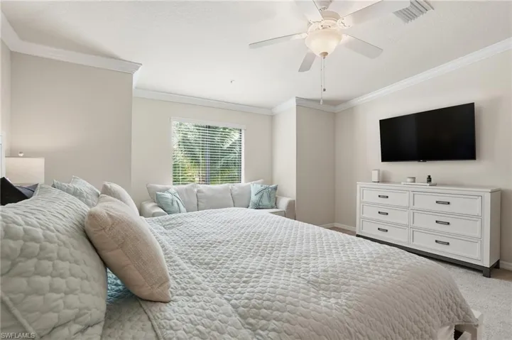 Carpeted bedroom featuring ceiling fan, crown molding, and a textured ceiling