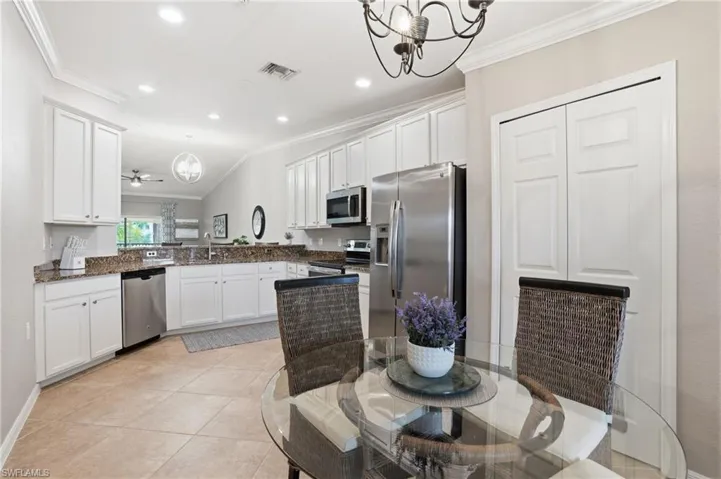 Kitchen featuring ornamental molding, hanging light fixtures, white cabinetry, appliances with stainless steel finishes, and recessed lighting