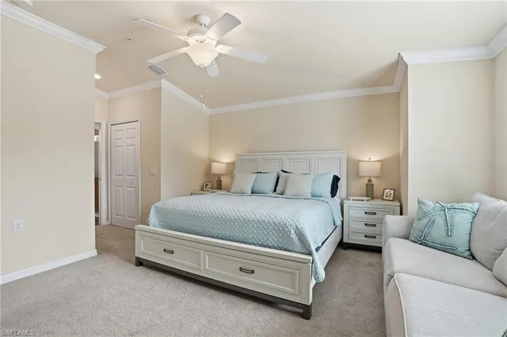 Carpeted bedroom with ornamental molding, ceiling fan, and a closet