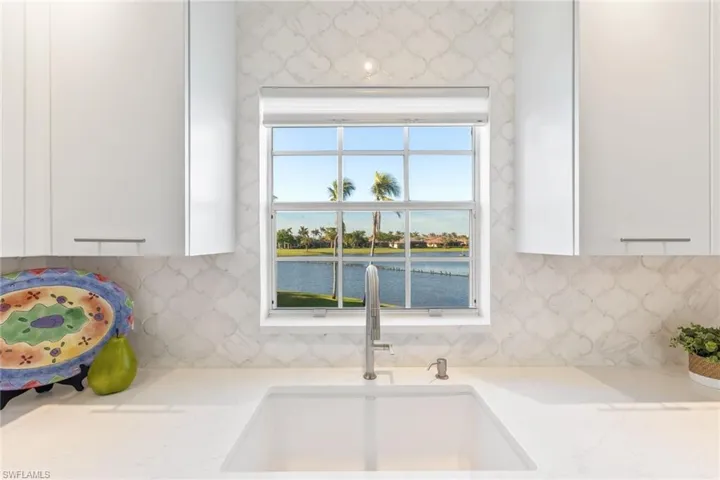 Interior details with white cabinetry, sink, decorative backsplash, and a water view