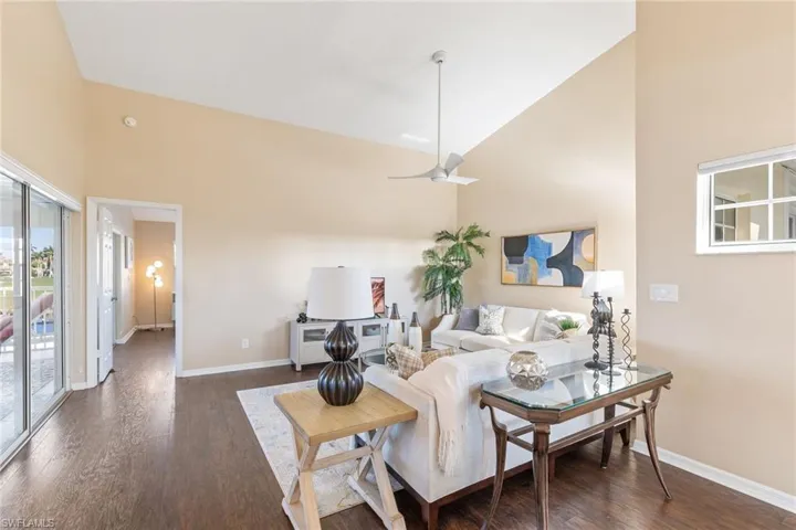 Living room featuring ceiling fan, dark wood-type flooring, and high vaulted ceiling