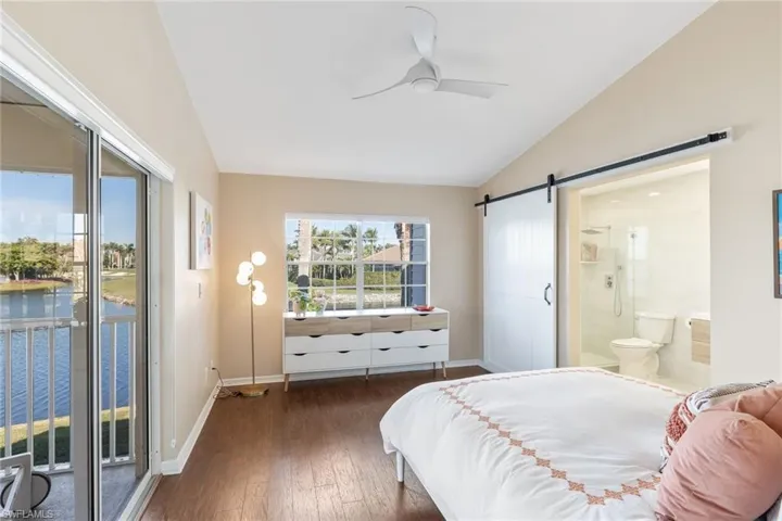 Bedroom featuring a barn door, vaulted ceiling, multiple windows, and access to outside