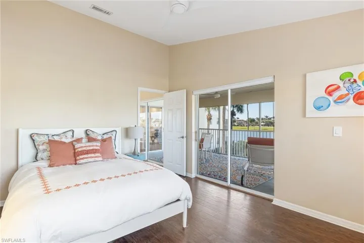 Bedroom with dark hardwood / wood-style flooring, access to exterior, and a water view