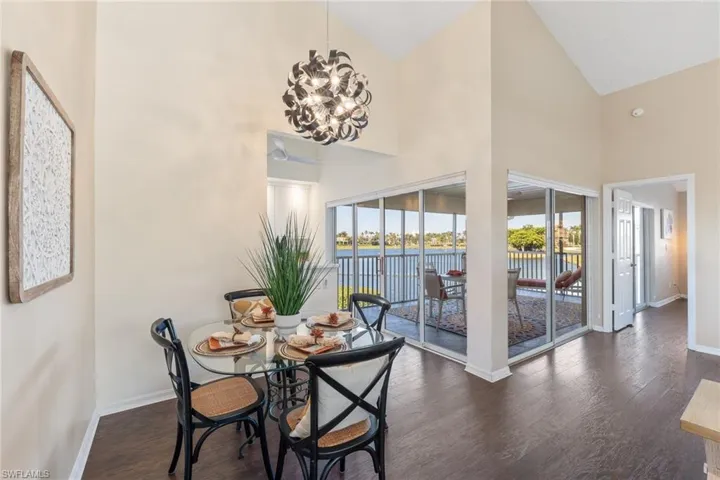 Dining room with a water view, dark hardwood / wood-style flooring, a chandelier, and high vaulted ceiling