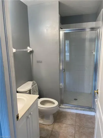 Bathroom featuring tile patterned floors, toilet, walk in shower, and vanity