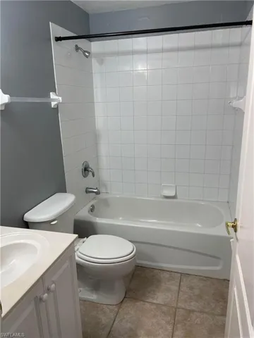 Full bathroom with tile patterned flooring, tiled shower / bath combo, vanity, and toilet