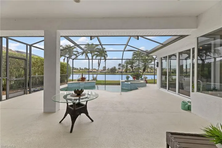 View of swimming pool featuring screen enclosure, a patio, a water view, and a pool with connected hot tub